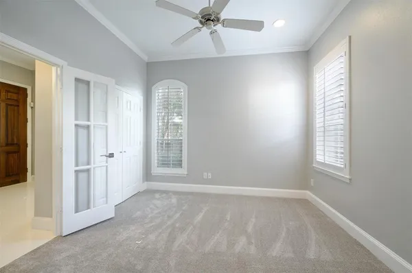 an empty room with wooden floor and way to kitchen