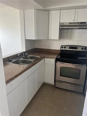 a kitchen with granite countertop white cabinets and stainless steel appliances