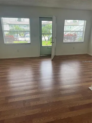 an empty room with wooden floor and windows