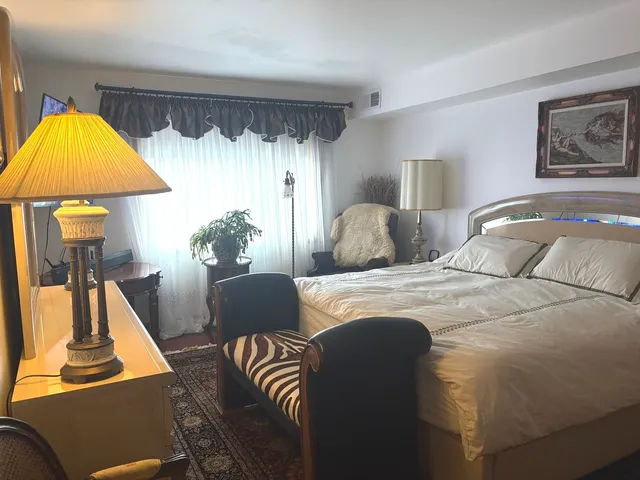 a spacious bedroom with a bed and a lamp