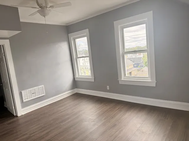 a view of an empty room with a window and wooden floor