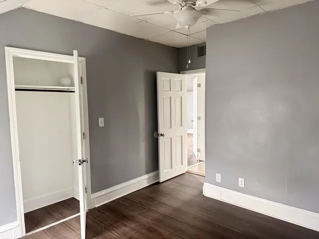 an empty room with wooden floor and a ceiling fan