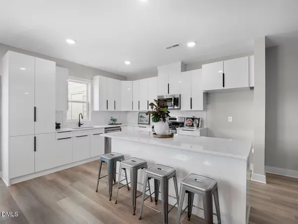 a kitchen with stainless steel appliances granite countertop a table chairs stove microwave and cabinets