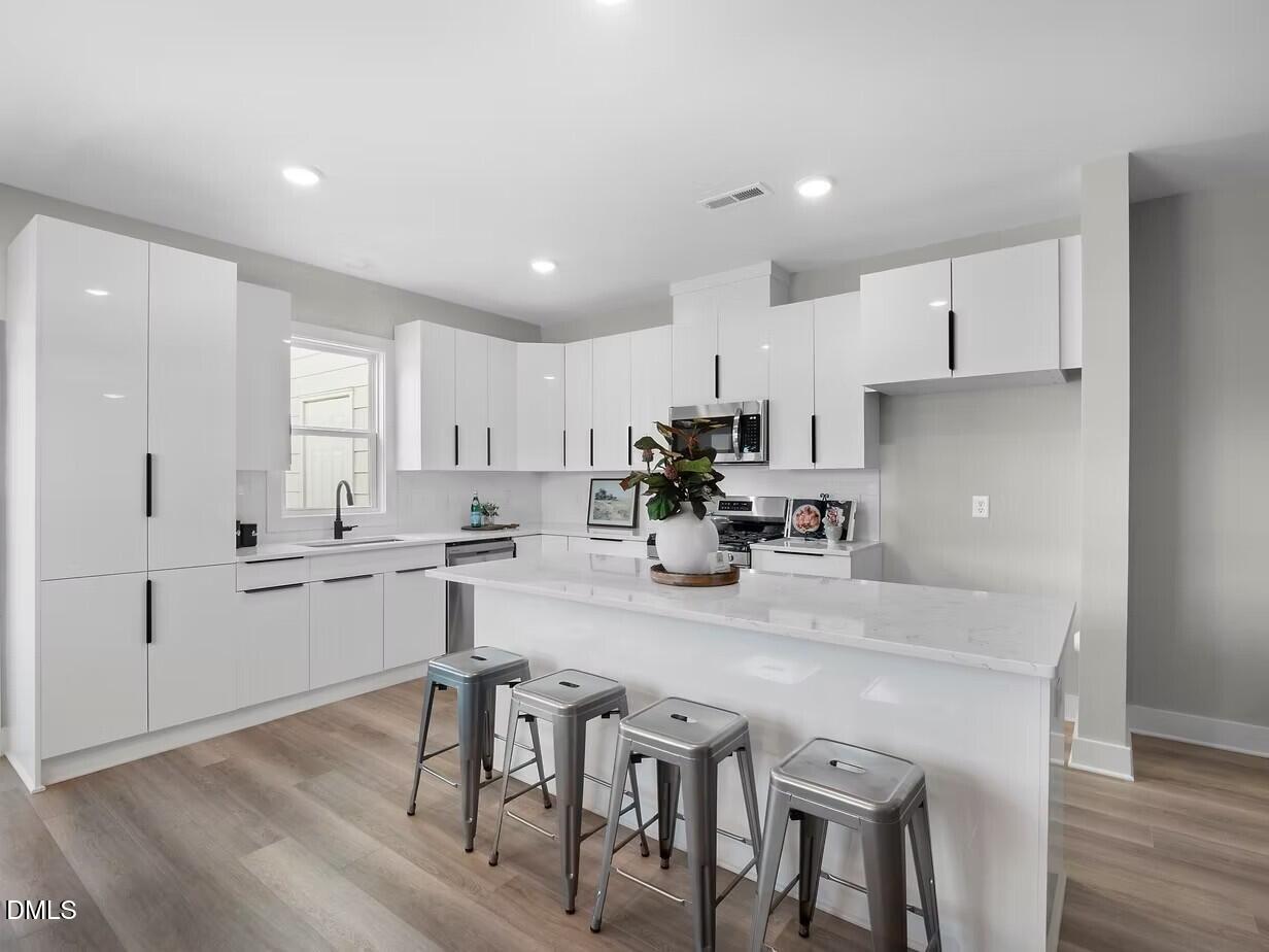 2126 Titanium Rock Road Durham, NC 27704 - Photo 4 of 20 a kitchen with stainless steel appliances granite countertop a table chairs stove microwave and cabinets