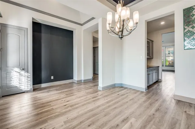 an empty room with wooden floor chandelier and windows