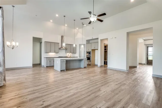 a view of a kitchen with kitchen island stainless steel appliances cabinets a sink and a wooden floor