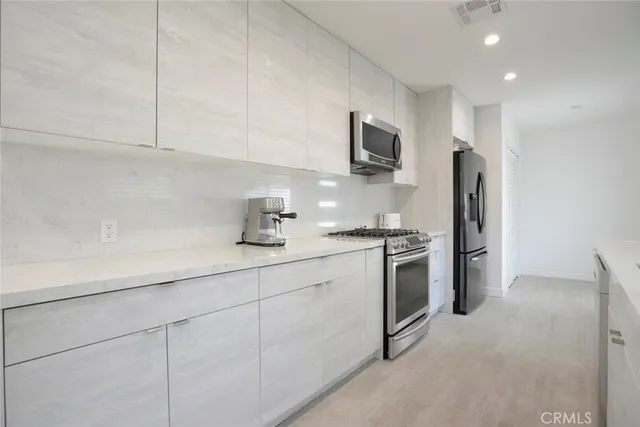 a kitchen with stainless steel appliances granite countertop a sink a stove a refrigerator and cabinets