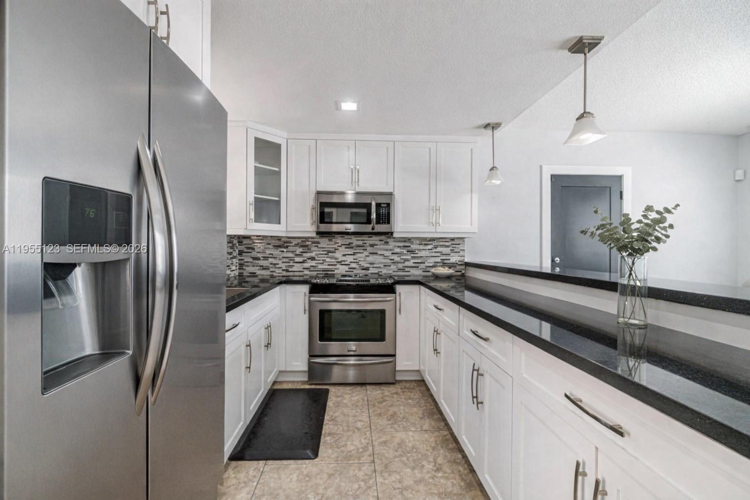 901 Northwest 22nd Place Miami, FL 33125 - Photo 9 of 52 a large kitchen with a refrigerator a sink a stove and cabinets