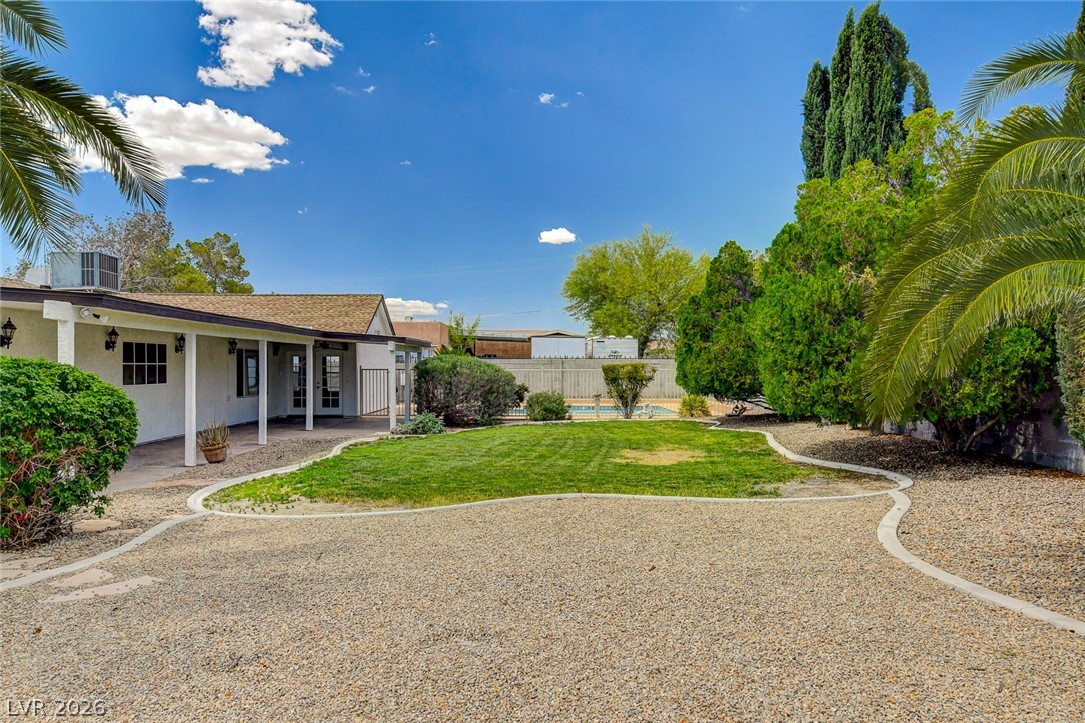 1810 Pinto Road Henderson, NV 89002 - Photo 44 of 53 A spacious backyard retreat with lush green lawn, mature trees, and ample gravel patio space.