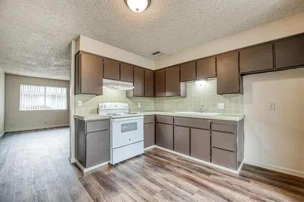 a kitchen with granite countertop a sink cabinets stainless steel appliances and a window