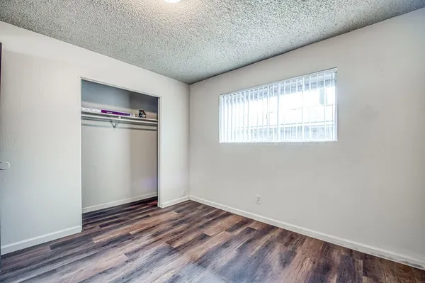 an empty room with wooden floor cabinet and windows