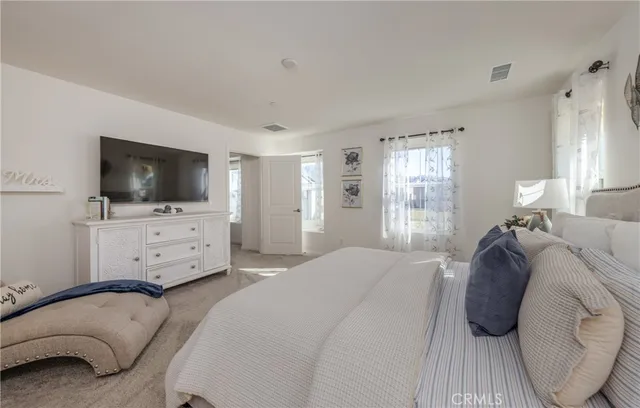 a bedroom with a bed and a flat tv screen on dresser
