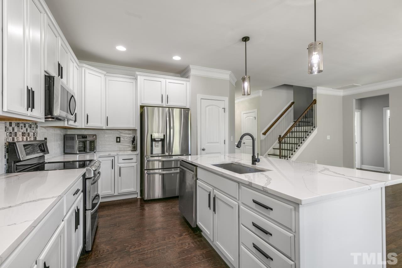 8340 Yellow Aster Court Willow Spring, NC 27592 - Photo 6 of 35 a kitchen with white cabinets and stainless steel appliances