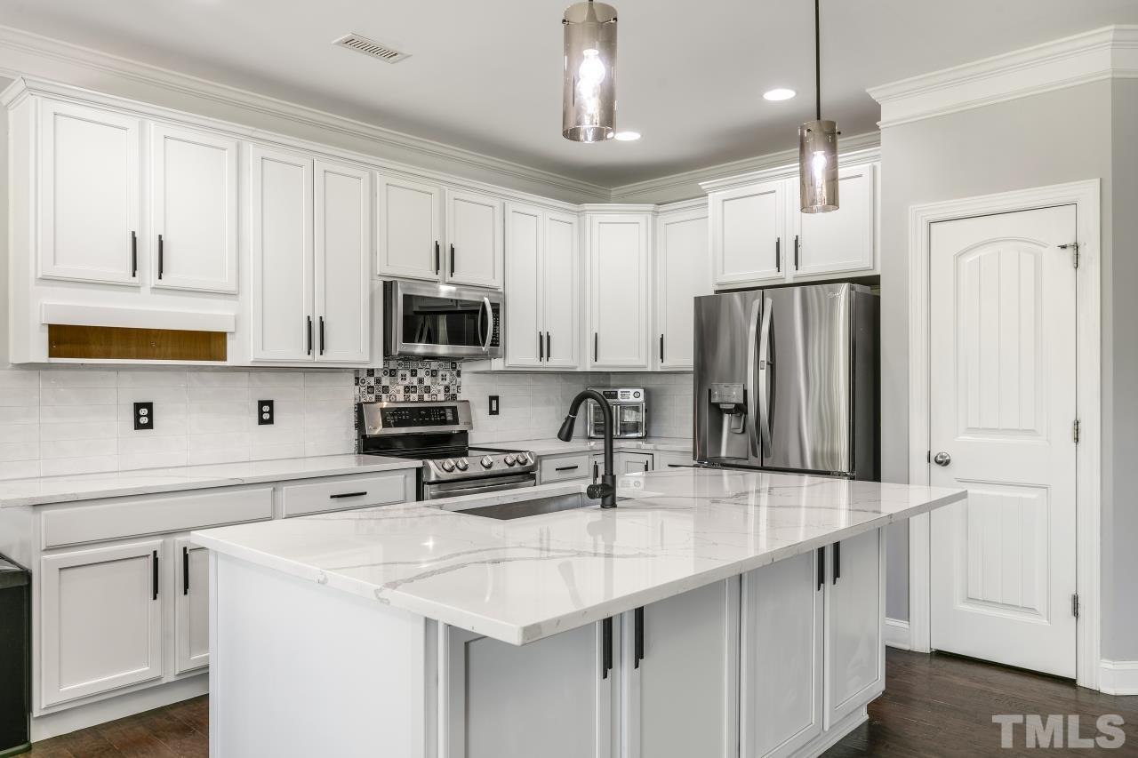 8340 Yellow Aster Court Willow Spring, NC 27592 - Photo 7 of 35 a kitchen with stainless steel appliances a sink stove and refrigerator