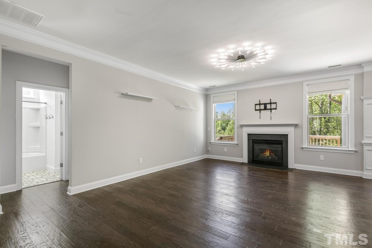 8340 Yellow Aster Court Willow Spring, NC 27592 - Photo 9 of 35 an empty room with wooden floor fireplace and windows