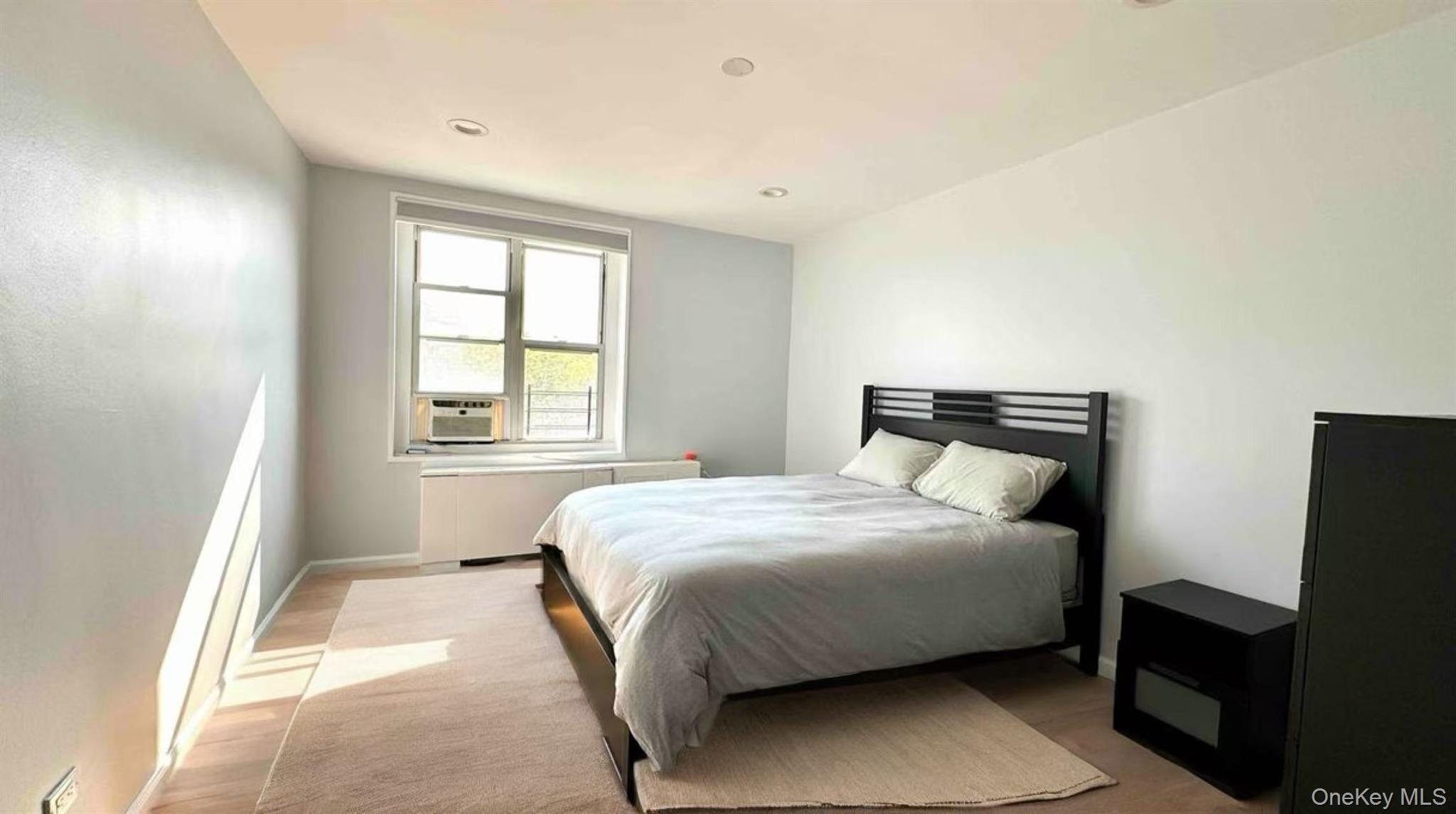 211-10 18th Avenue, Unit 6C Queens, NY 11360 - Photo 6 of 16 a bedroom with a bed and wooden floor