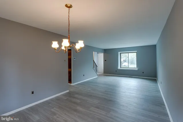 a view of a room with a chandelier fan and a wooden floor