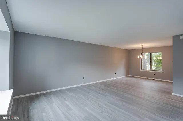 a view of an empty room with wooden floor and window