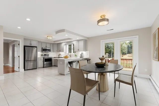 a kitchen with stainless steel appliances kitchen island granite countertop a sink a stove a refrigerator cabinets and a dining table with chairs