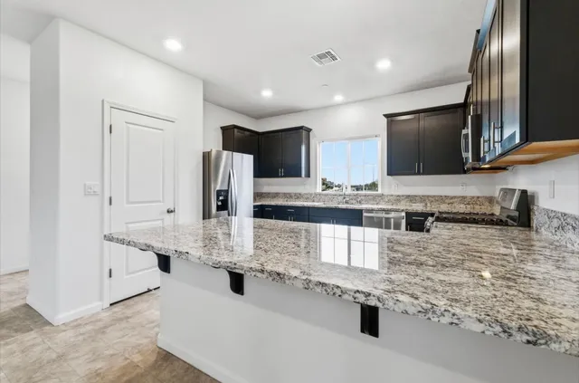 a kitchen with stainless steel appliances granite countertop a refrigerator and a stove top oven