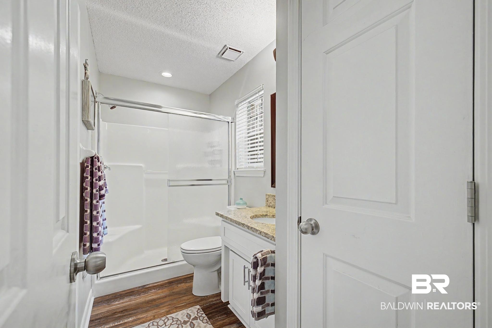 2808 Pine Ridge Drive Lillian, AL 36549 - Photo 23 of 47 Full bathroom featuring a white vanity with a granite-style countertop, a white toilet, and a shower with a sliding glass door
