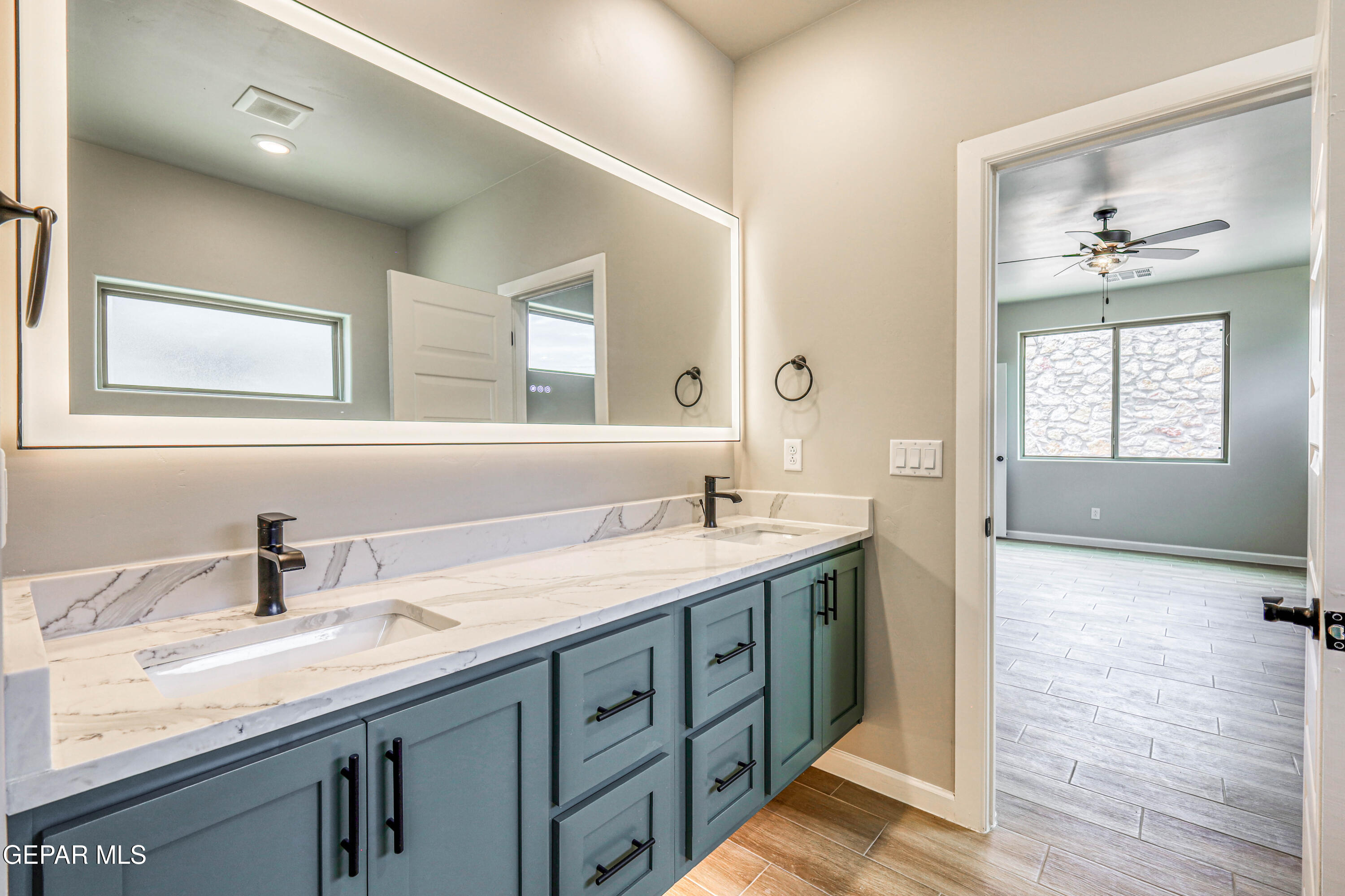 6047 Zinc Hill Street Sunland Park, NM 88008 - Photo 15 of 18 a bathroom with a granite countertop sink a large mirror and next to a window