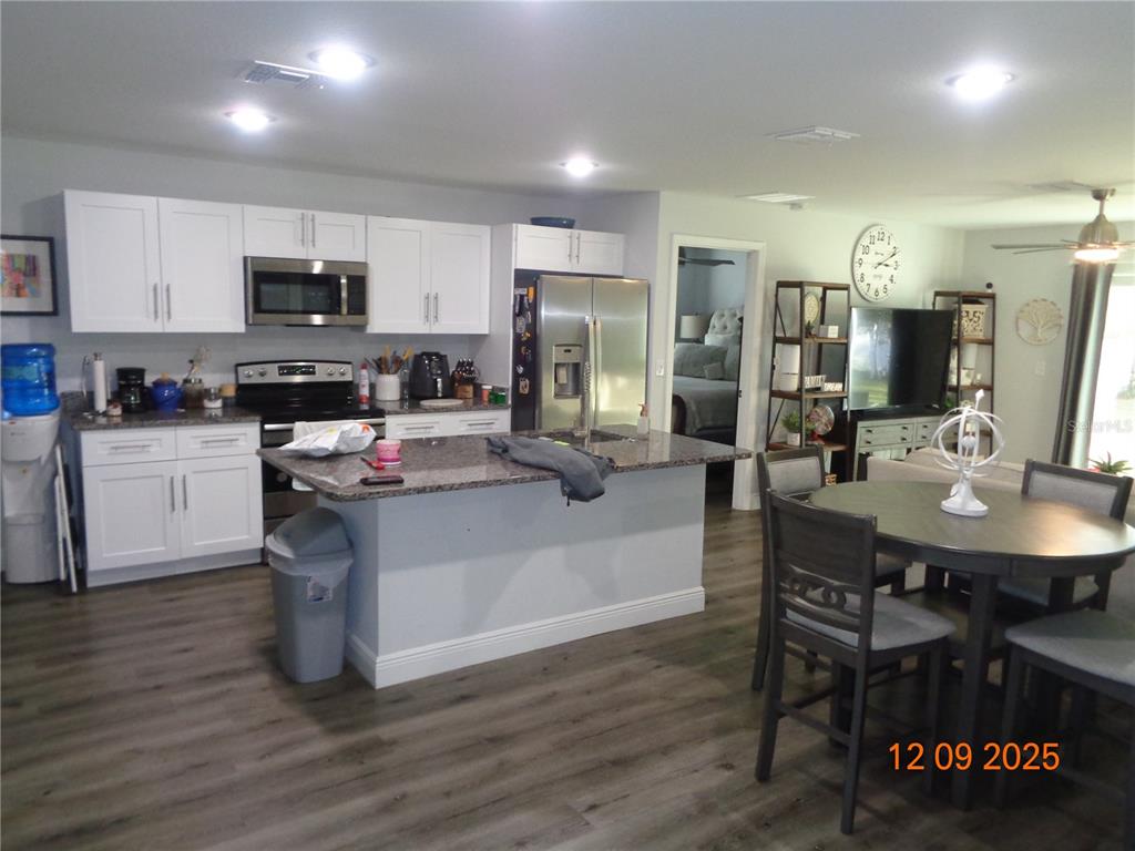 2380 8th Avenue DeLand, FL 32724 - Photo 18 of 31 a kitchen with stainless steel appliances granite countertop a sink dishwasher a stove a refrigerator a microwave oven with a dining table and chairs