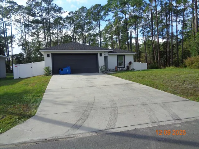 a front view of house with yard and trees in the background