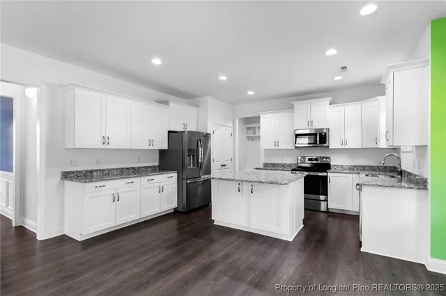 a kitchen with granite countertop white cabinets and refrigerator