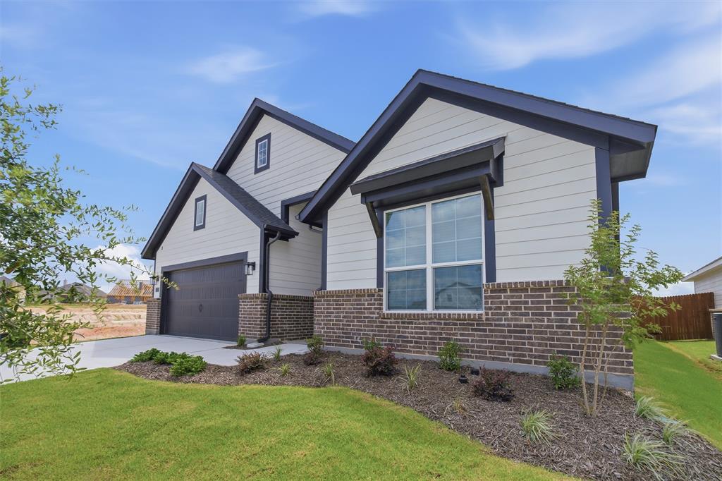 1325 Frio Drive Springtown, TX 76082 - Photo 4 of 24 Modern home exterior featuring light horizontal siding, dark trim, a dark gray garage door, and a brick facade