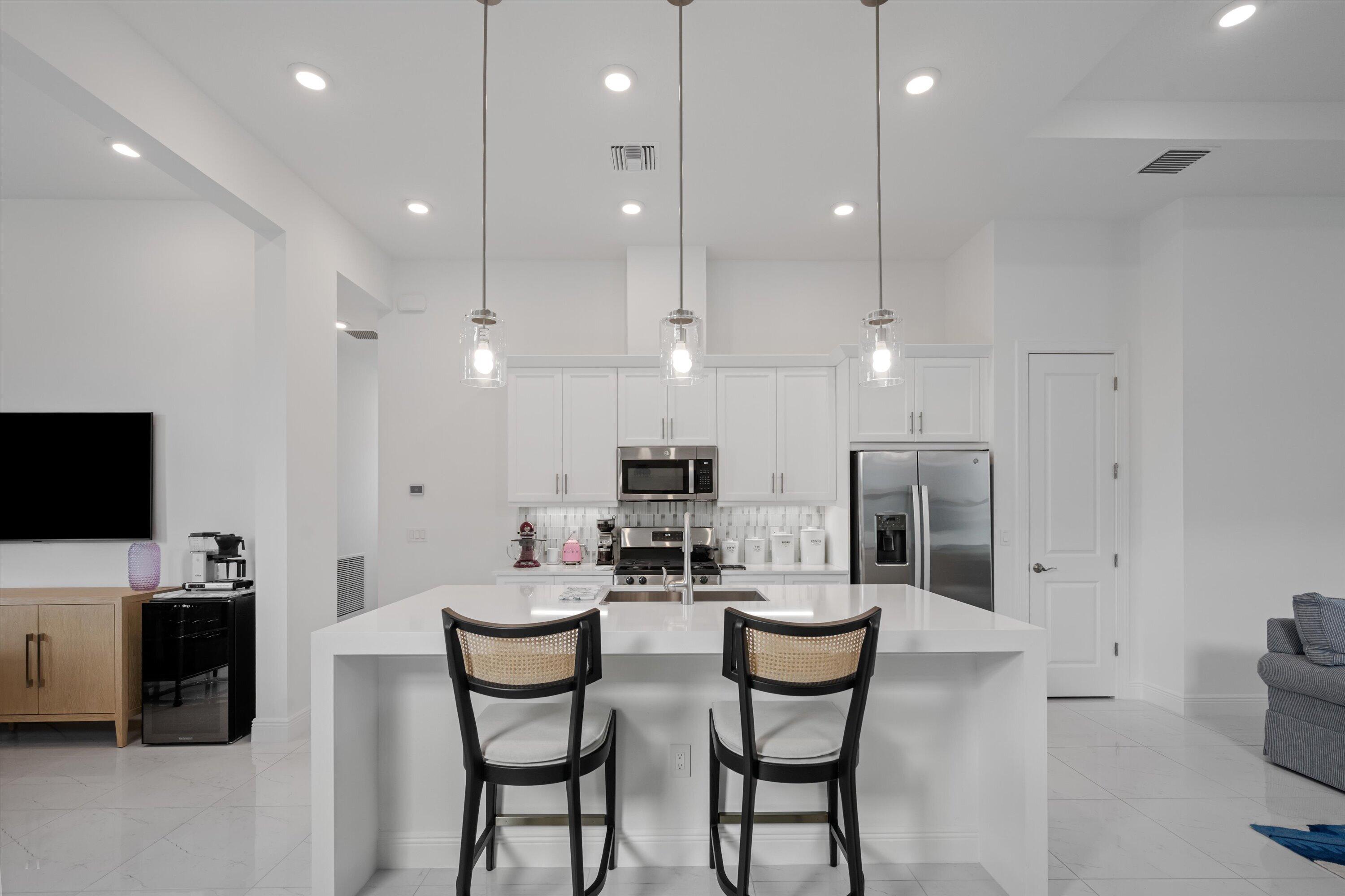 4891 Rivo Alto Circle Loxahatchee, FL 33470 - Photo 11 of 64 a kitchen with stainless steel appliances kitchen island granite countertop a stove a sink a refrigerator and a dining table with white cabinets