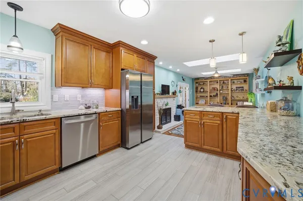 a kitchen with stainless steel appliances granite countertop a refrigerator a stove and a sink with wooden floor