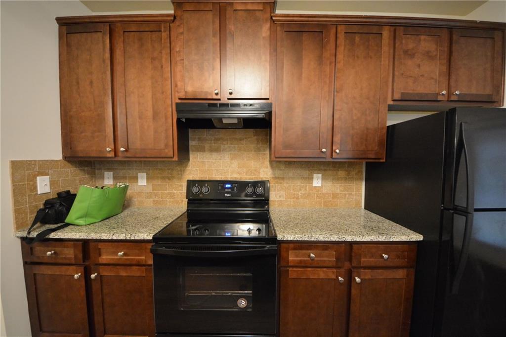 4305 Traipse Path Ellenwood, GA 30294 - Photo 18 of 36 a kitchen with granite countertop wood cabinets and stainless steel appliances