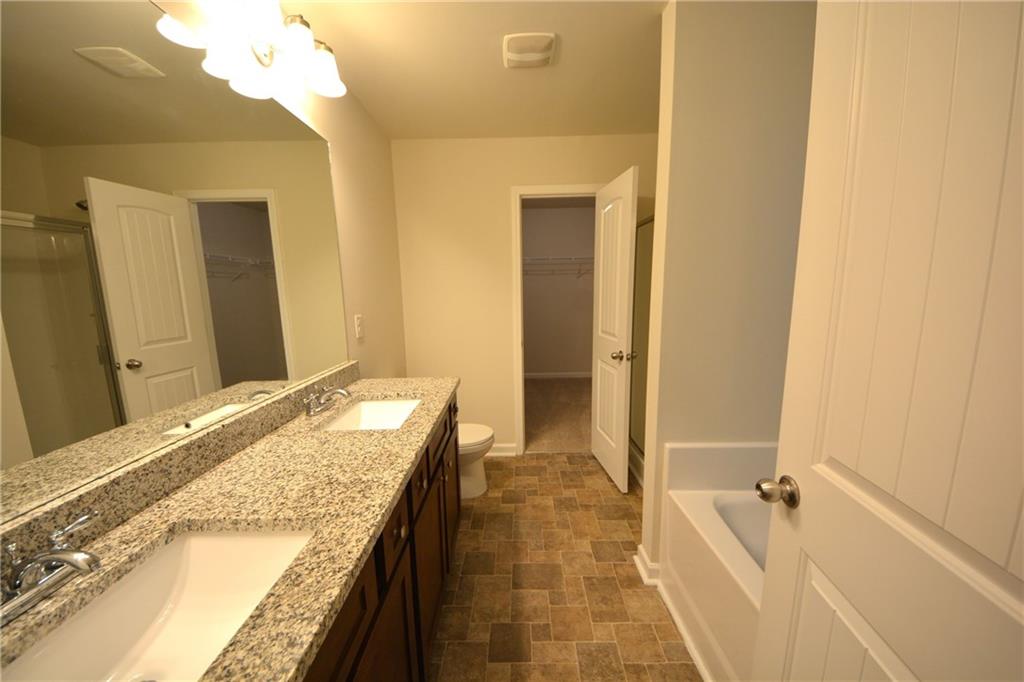 4305 Traipse Path Ellenwood, GA 30294 - Photo 26 of 36 a spacious bathroom with a granite countertop sink and a mirror