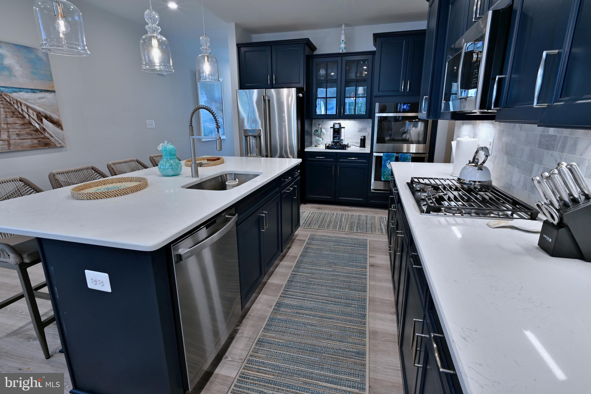 19277 American Holly Road Rehoboth Beach, DE 19971 - Photo 26 of 28 a kitchen with kitchen island stainless steel appliances a sink stove and cabinets