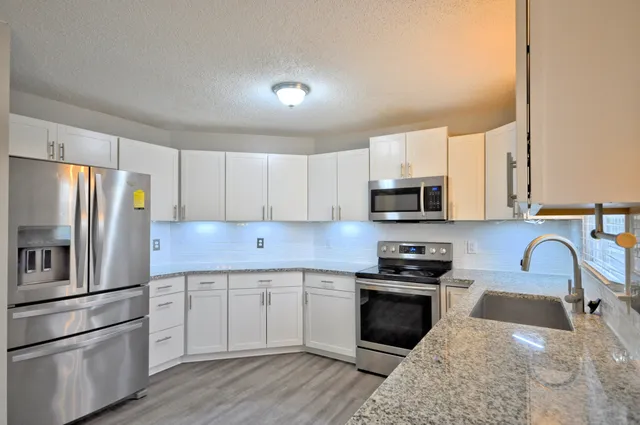 a kitchen with granite countertop a refrigerator stove and sink