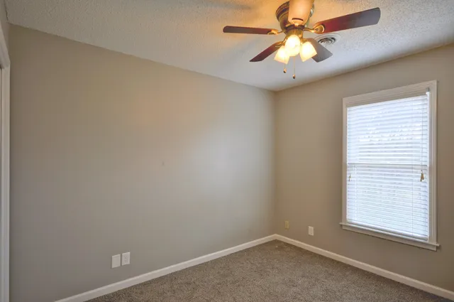 an empty room with a window and a fan