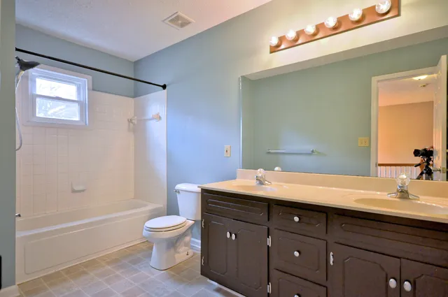 a bathroom with a granite countertop sink toilet a large mirror a bathtub and shower