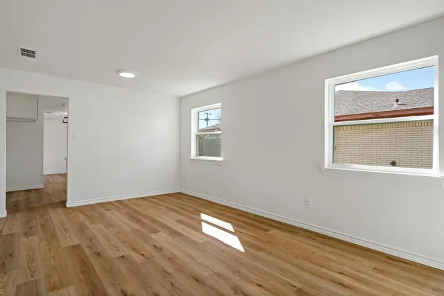 a view of empty room with wooden floor and fan