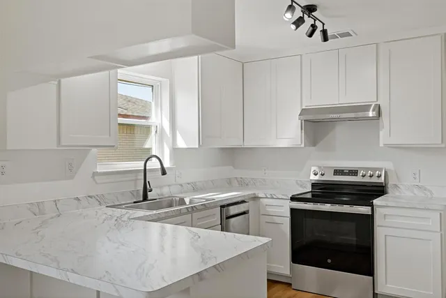 a kitchen with granite countertop a sink a stove and cabinets