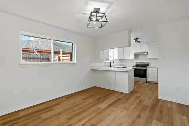 a kitchen with granite countertop a stove cabinets and wooden floor