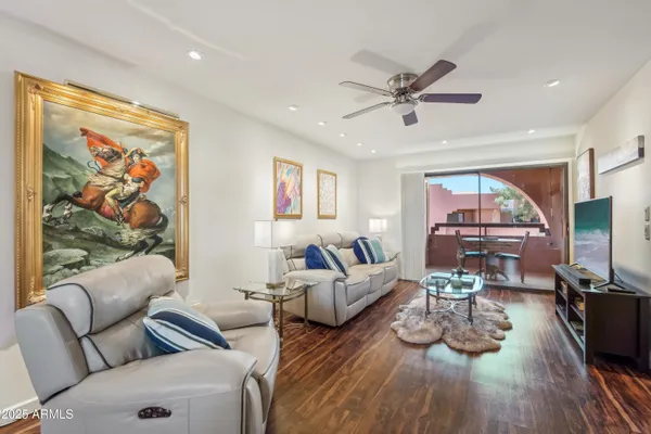 a living room with furniture a flat screen tv and a ceiling fan