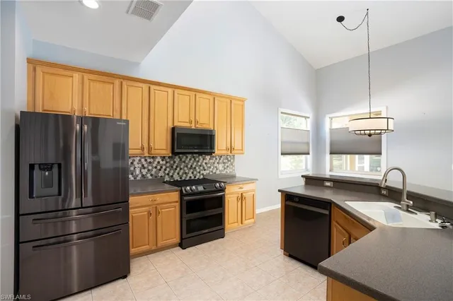 a kitchen with stainless steel appliances granite countertop a refrigerator a stove a sink and a microwave