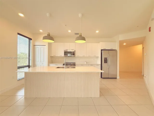 a kitchen with stainless steel appliances a stove a refrigerator a sink a center island and chairs