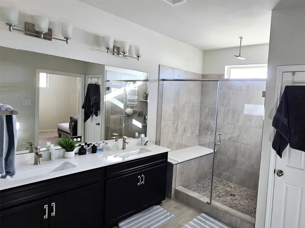 a bathroom with a double vanity sink mirror and shower