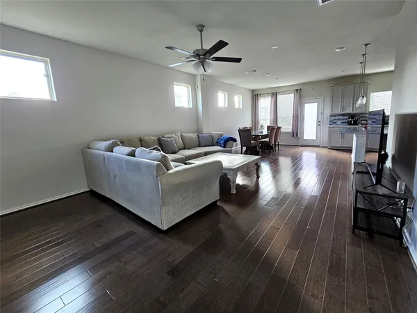 a living room with couches and kitchen view with wooden floor