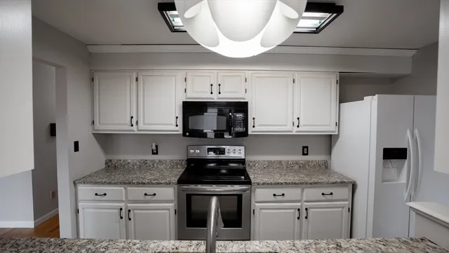 a kitchen with stainless steel appliances granite countertop a stove a refrigerator and a microwave