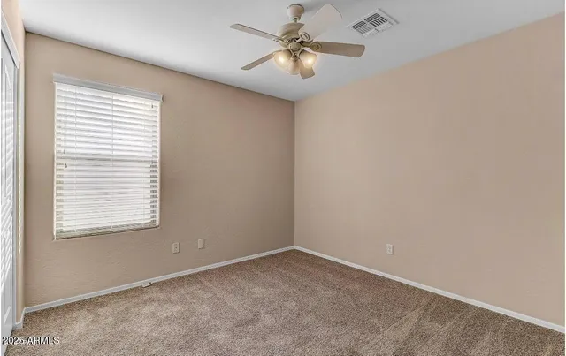 an empty room with windows and fan