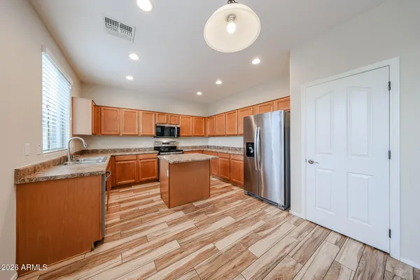 a large kitchen with stainless steel appliances granite countertop a refrigerator a sink dishwasher a stove and white countertops with wooden floor