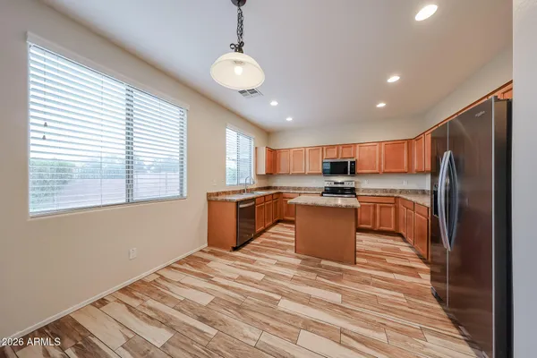 a large kitchen with stainless steel appliances granite countertop a refrigerator a sink dishwasher a stove and a microwave oven with wooden floor